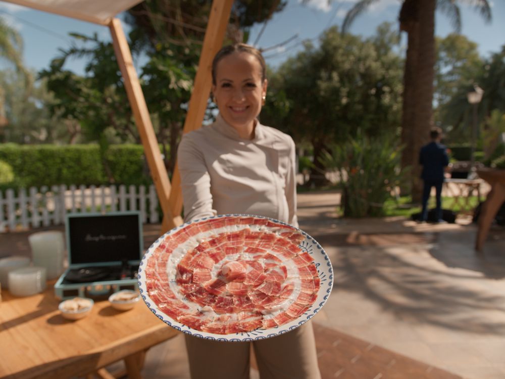 Mireia Sanchis cortando jamón ibérico a cuchillo en evento corporativo en Valencia