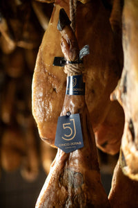 bellotaJamón de bellota 100% ibérico Cinco Jotas 5J con etiqueta negra colgado en bodega de Jabugo
