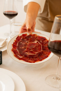 Plato de jamón de cebo ibérico cortado a mano servido con vino tinto